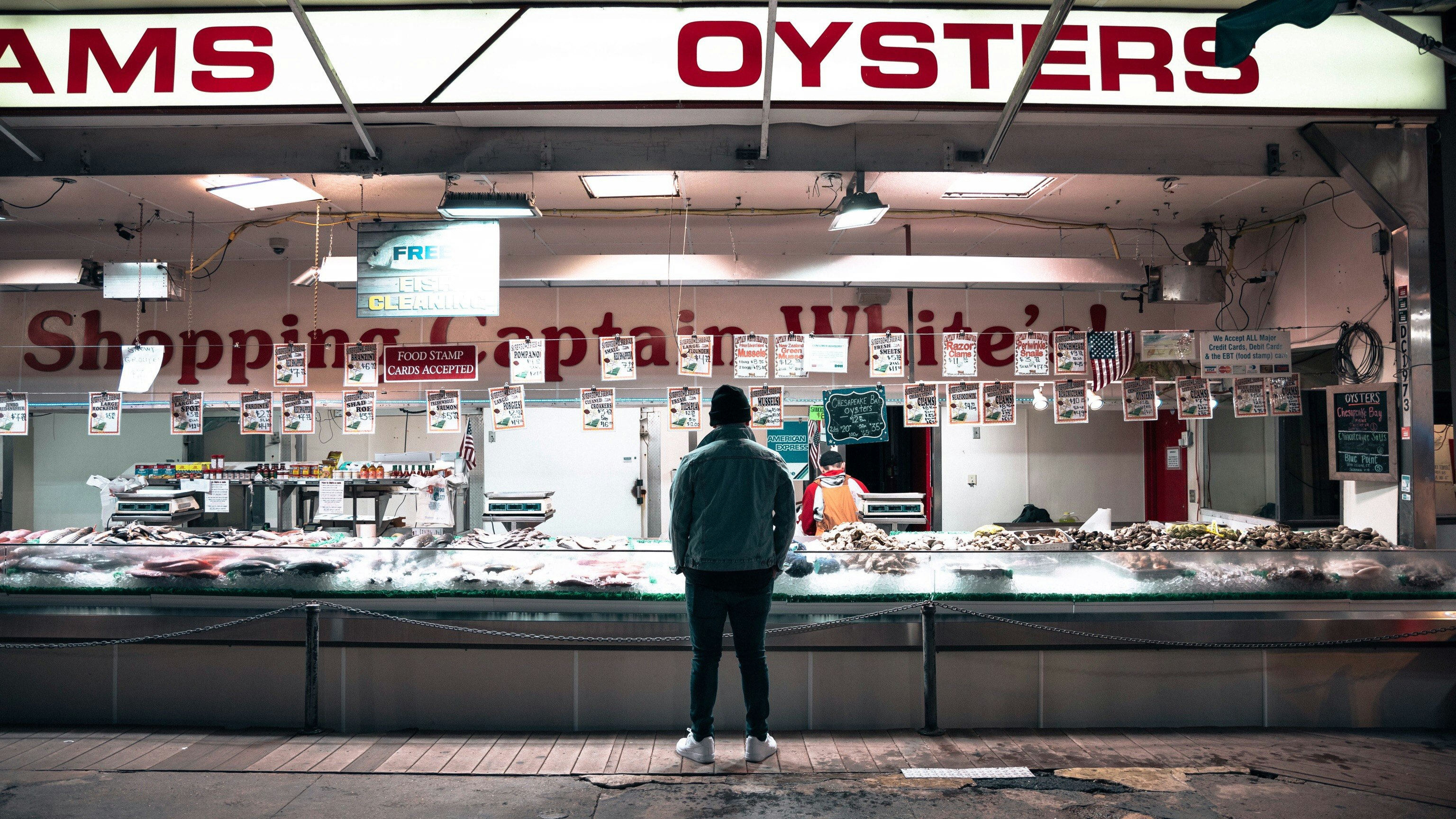 man in black jacket standing in front of store